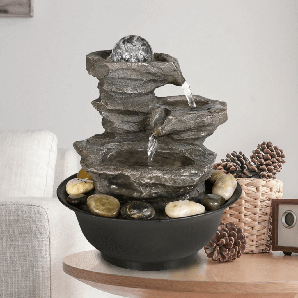 A tabletop fountain with water cascading from a glass orb down natural stone-like tiers
