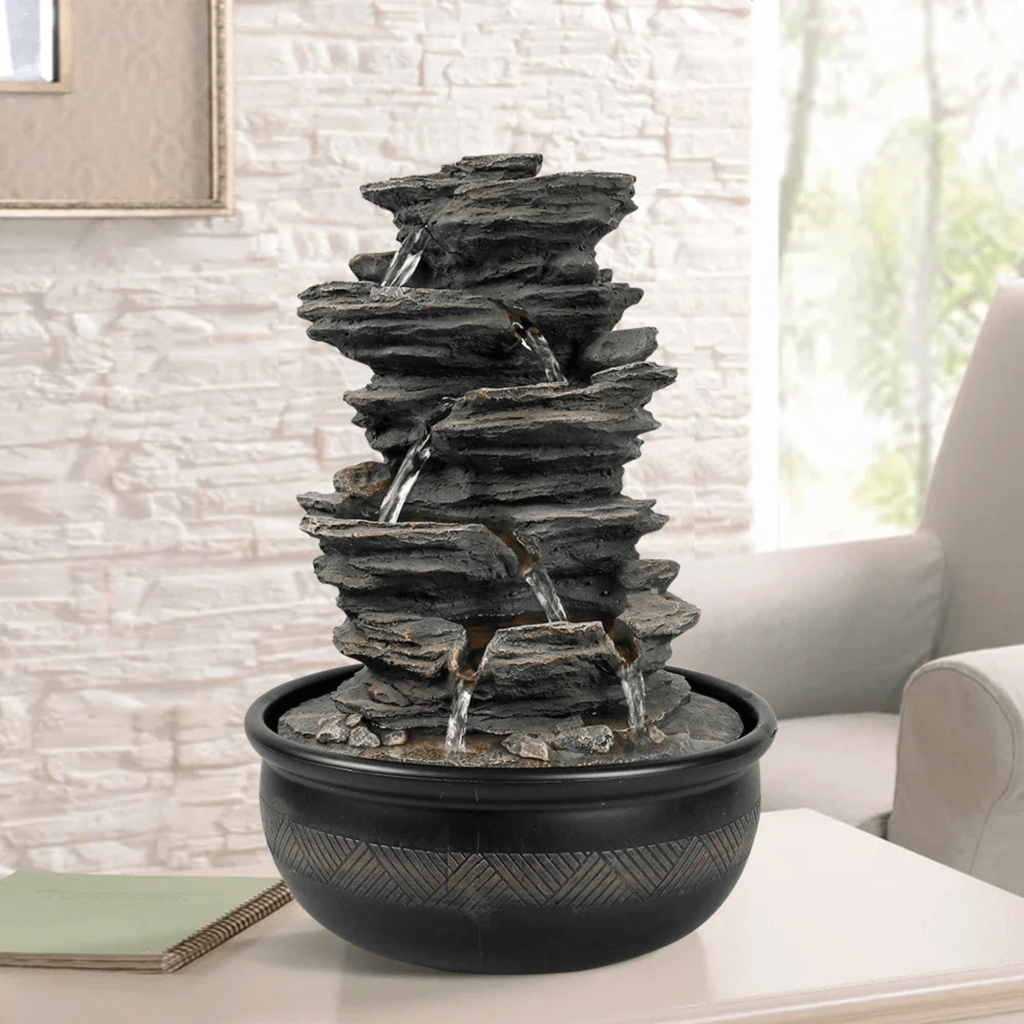 A multi-tiered tabletop fountain with water cascading down natural stone-like layers