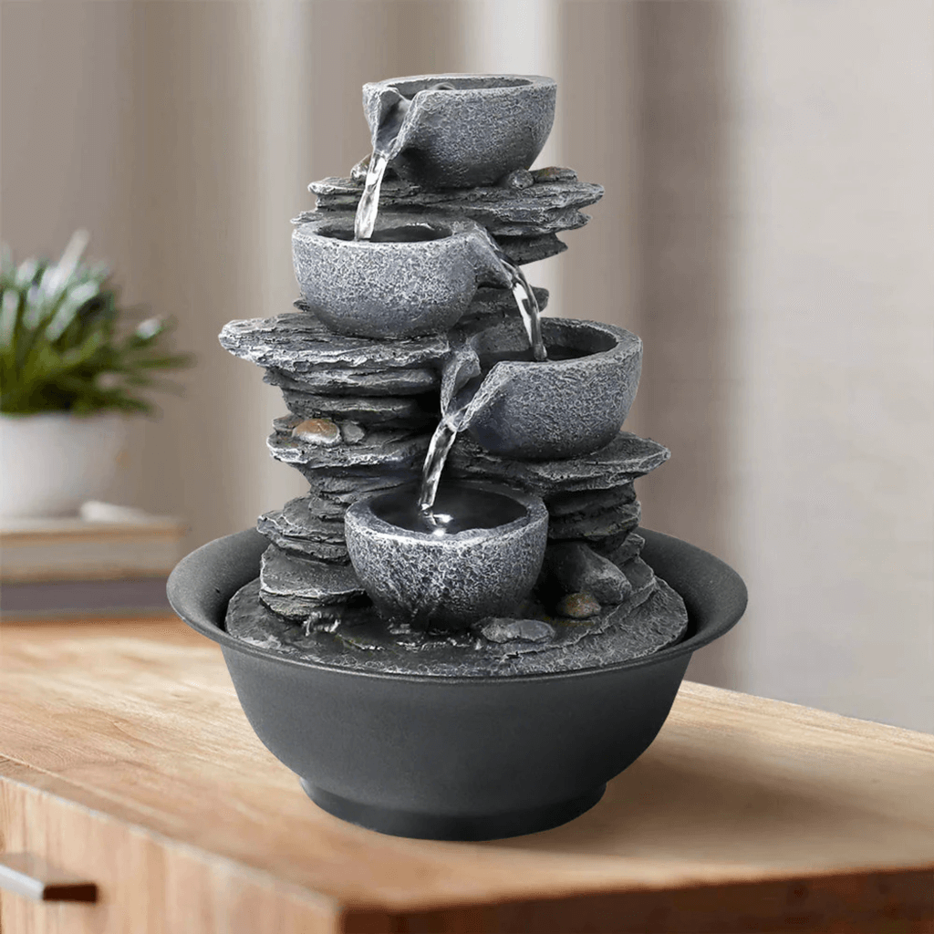 A tabletop fountain with water cascading through a series of stone-like bowls