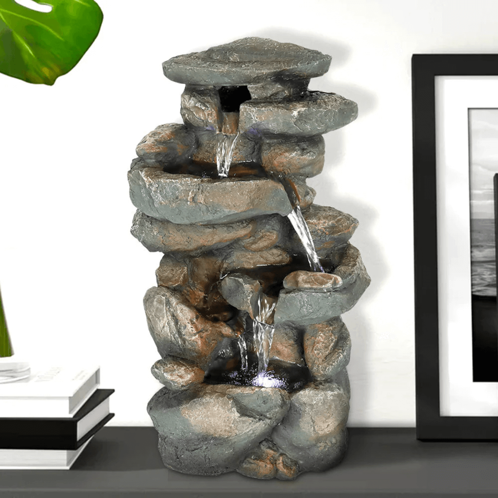 A tabletop fountain with water cascading over stacked stone-like formations